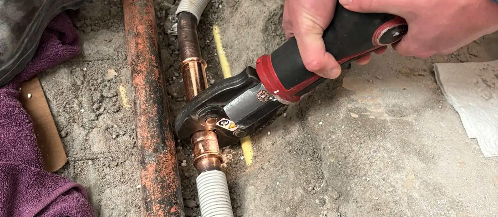 Phil perst een koperen koppeling in een lekkende waterleiding