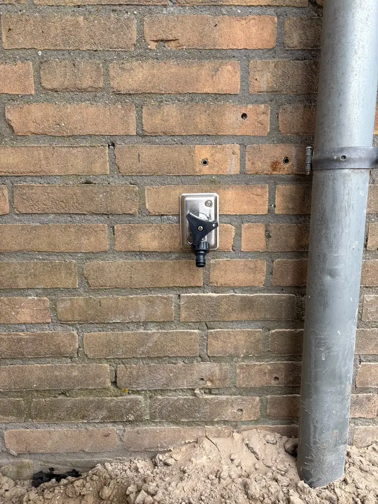 Nieuw geplaatste vorstvrije buitenkraan met slangkoppeling in de gevel van een woning in Helmond
