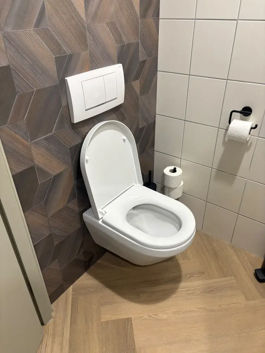 Witte tweeknops-drukplaat boven een hangtoilet; achter deze plaat staat de code op het inbouwreservoir