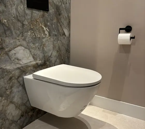 Strak geplaatst hangtoilet tegen een marmeren wand, aangesloten door een loodgieter in Helmond