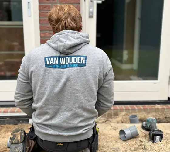 Phil van Wouden legt in bedrijfskleding een nieuwe rioolaansluiting aan bij een woning in Helmond