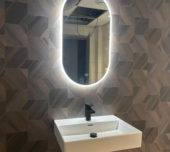 Zwevende wastafel met zwarte kraan en verlichte spiegel, geïnstalleerd in Helmond