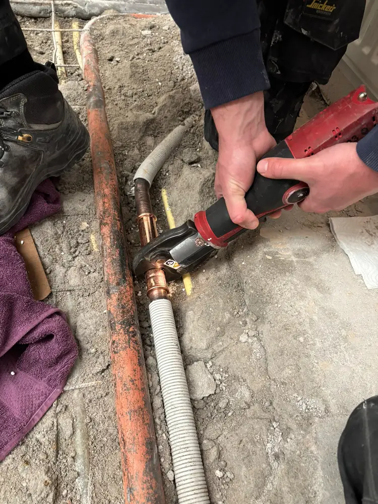 Loodgieter perst een koperen koppeling in een waterleiding tijdens het herstellen van een lekkage in Helmond