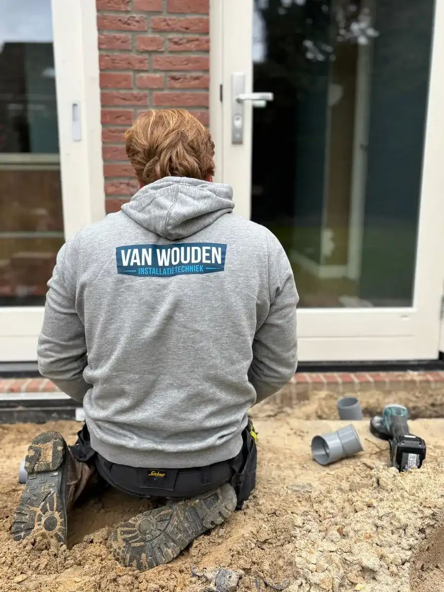 Phil van Wouden legt in bedrijfskleding een nieuwe rioolaansluiting aan bij een woning in Helmond