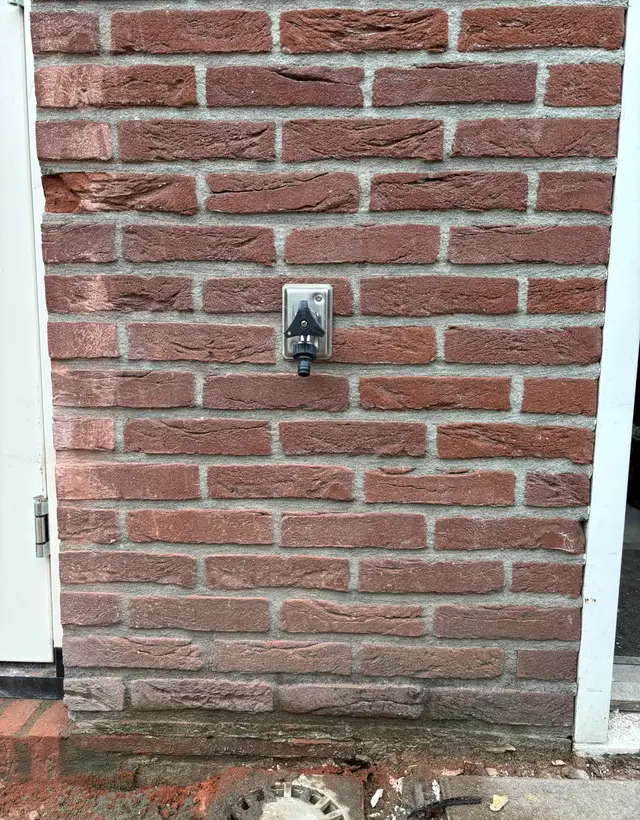 Vorstvrije buitenkraan gemonteerd in een rode bakstenen gevel naast de achterdeur