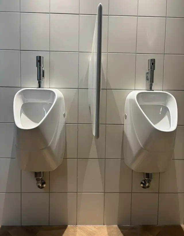 Twee urinoirs met spoelkranen, aangesloten in het toiletblok van een bedrijfspand