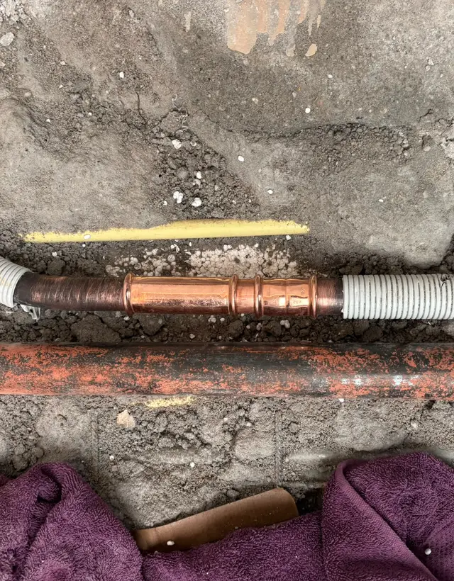 Nieuwe koperen koppeling in een waterleiding onder de vloer, vakkundig geperst en afgewerkt